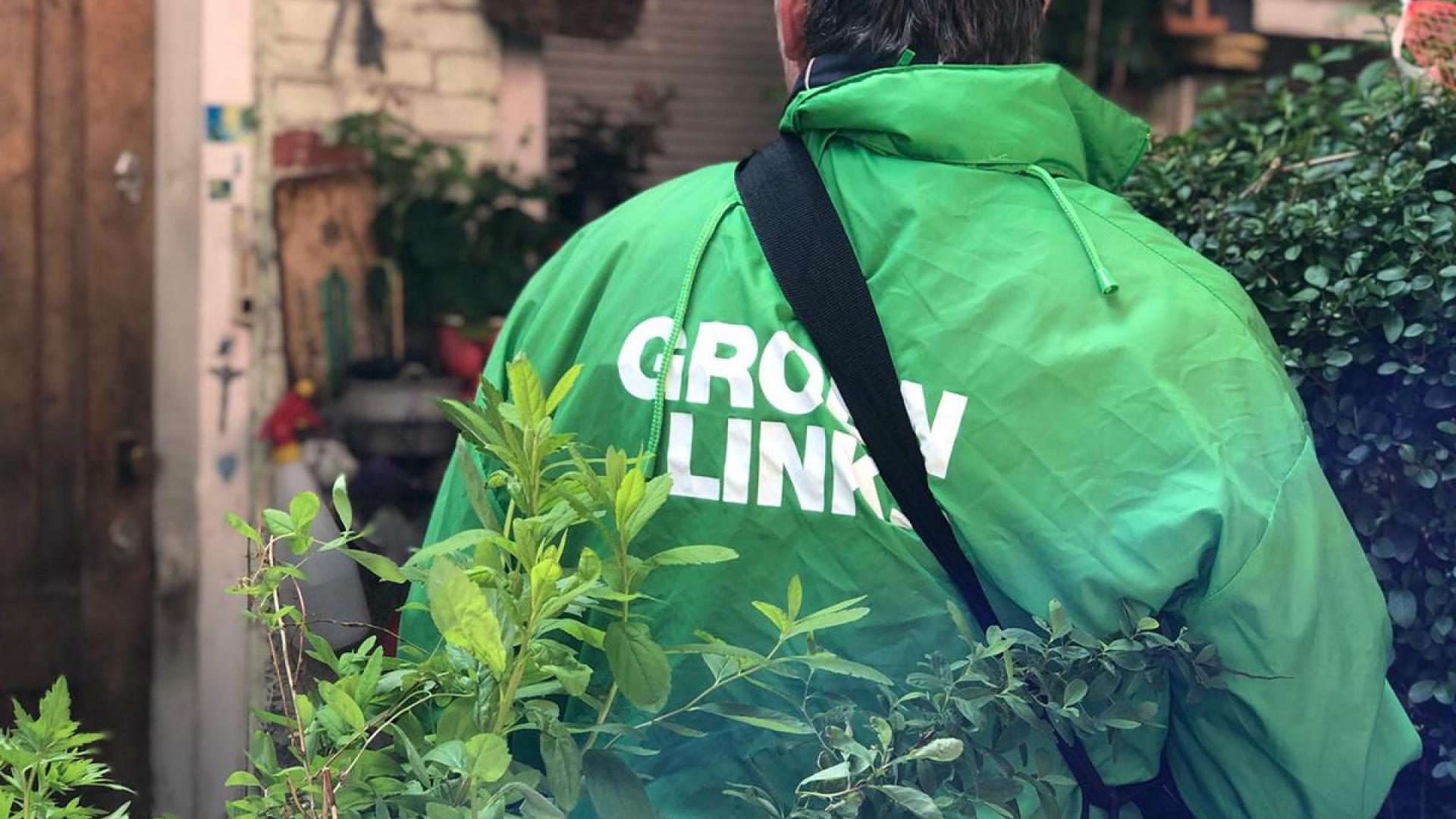 Een GroenLinks-vrijwilliger met een groene campagnejas aan en een GroenLinks-tas om